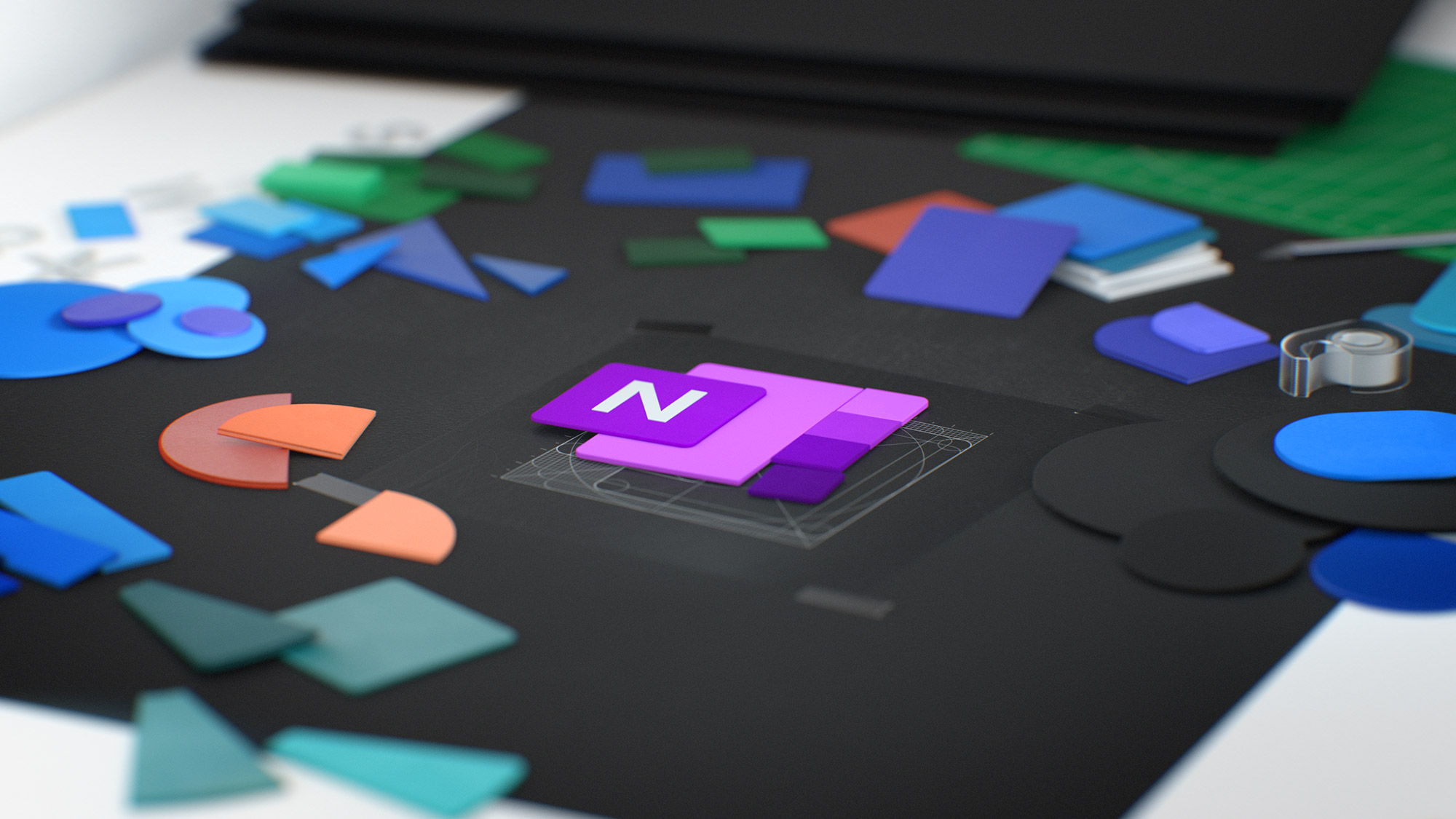 A neatly arranged desk features colorful geometric shapes and office supplies. At the center, there is a square paper with a purple layered shape with an "N" on it. Scattered around are shapes in blue, orange, green, and purple, along with some notebooks and tape rolls.