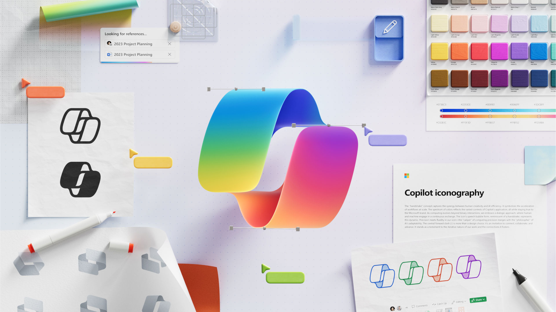 A colorful, abstract, swirling ribbon is centered on a desk scattered with design materials. Various color swatches, sketches of the ribbon logo, notes on "Copilot iconography," and other creative tools and papers surround the ribbon symbol.