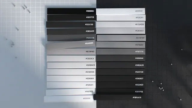 A gradient color scale image featuring a range of shades from black to white, with varying gray tones in between. Each shade is labeled with its hex color code. The background has a gray and black grid pattern, with a few small scattered silver spheres.