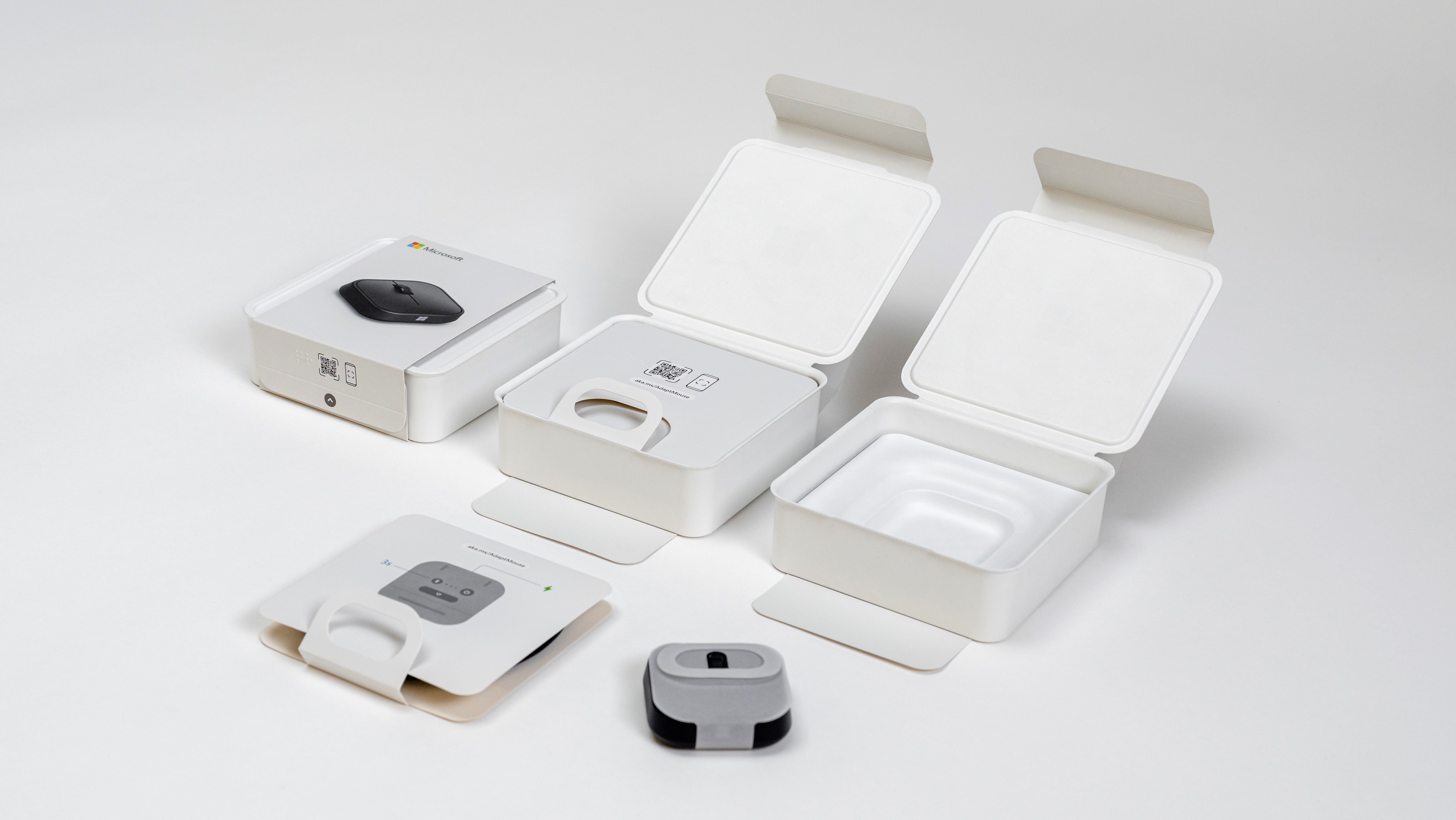 Minimalist product packaging design featuring two white rectangular boxes, each with a small electronic device inside. The boxes are open, displaying sleek, modern devices and their compact packaging layout on a light gray background.