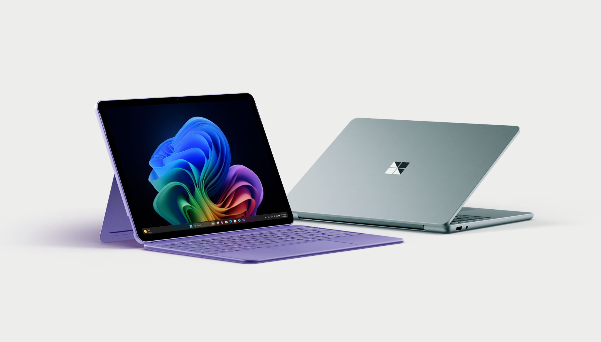 Two sleek laptops are displayed on a white background. One laptop is open, showing a vibrant, colorful swirl on its screen, while the other is closed, highlighting a reflective logo on its lid.