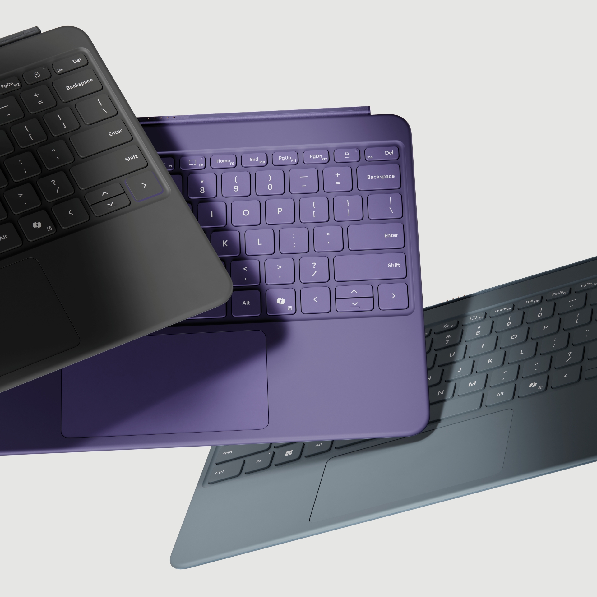 Three laptop keyboards in black, purple, and dark teal are arranged in an overlapping, diagonal layout on a light background, showcasing their keys and trackpads.