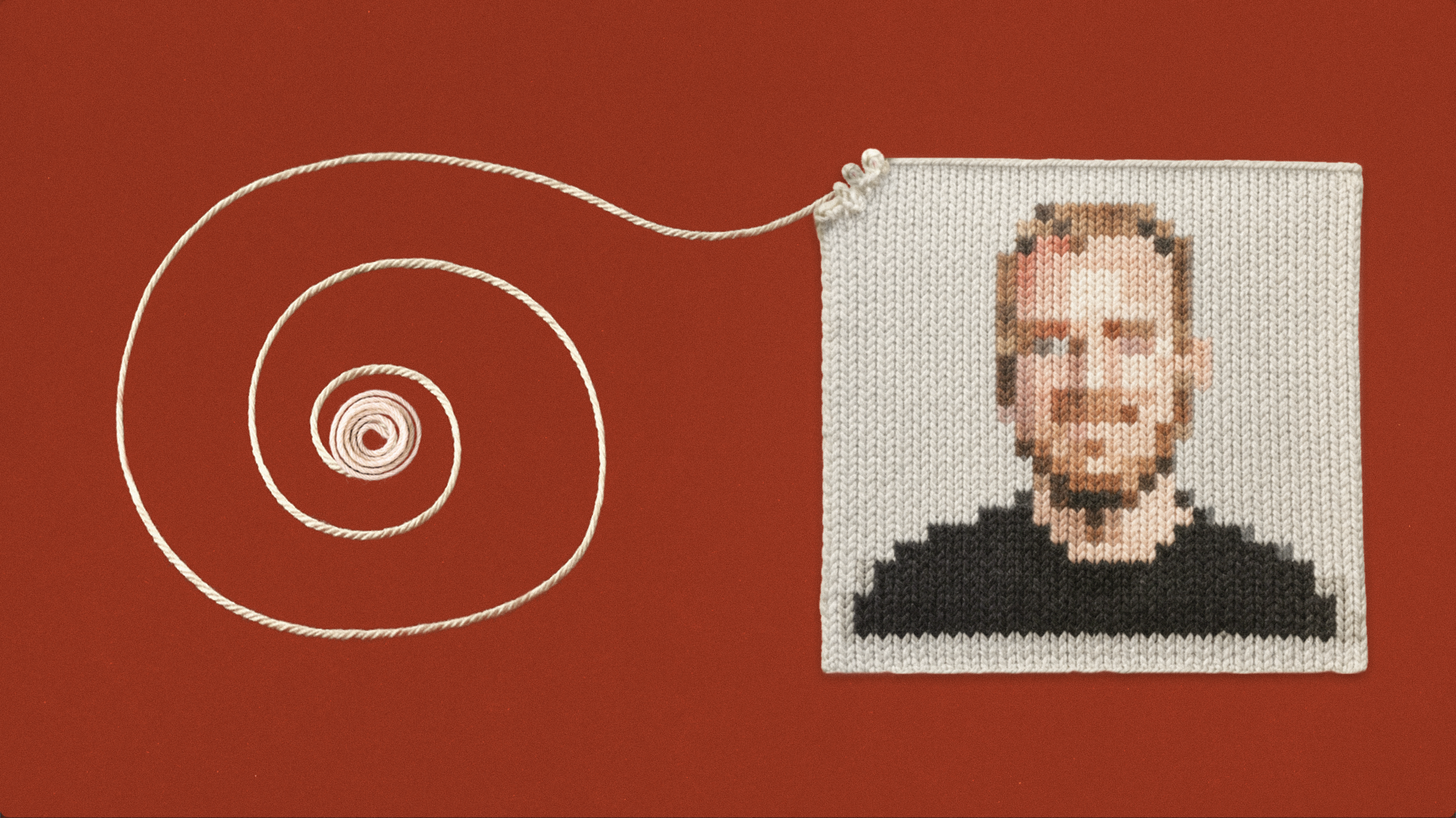 A pixelated portrait of a man’s face is knitted on fabric, attached to a white yarn spiraling outward on a red background.