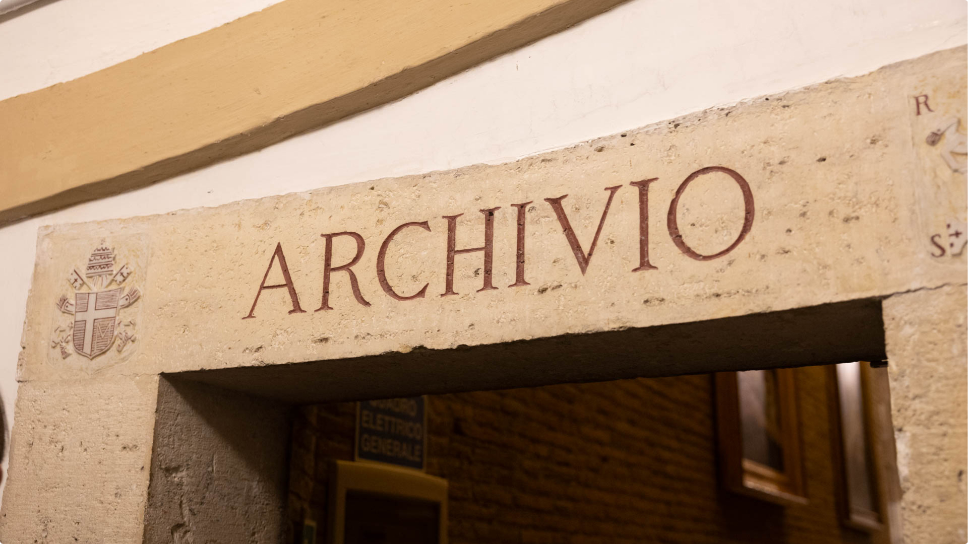 Stone doorway lintel inscribed with the word “ARCHIVIO” and a papal coat of arms to the left.