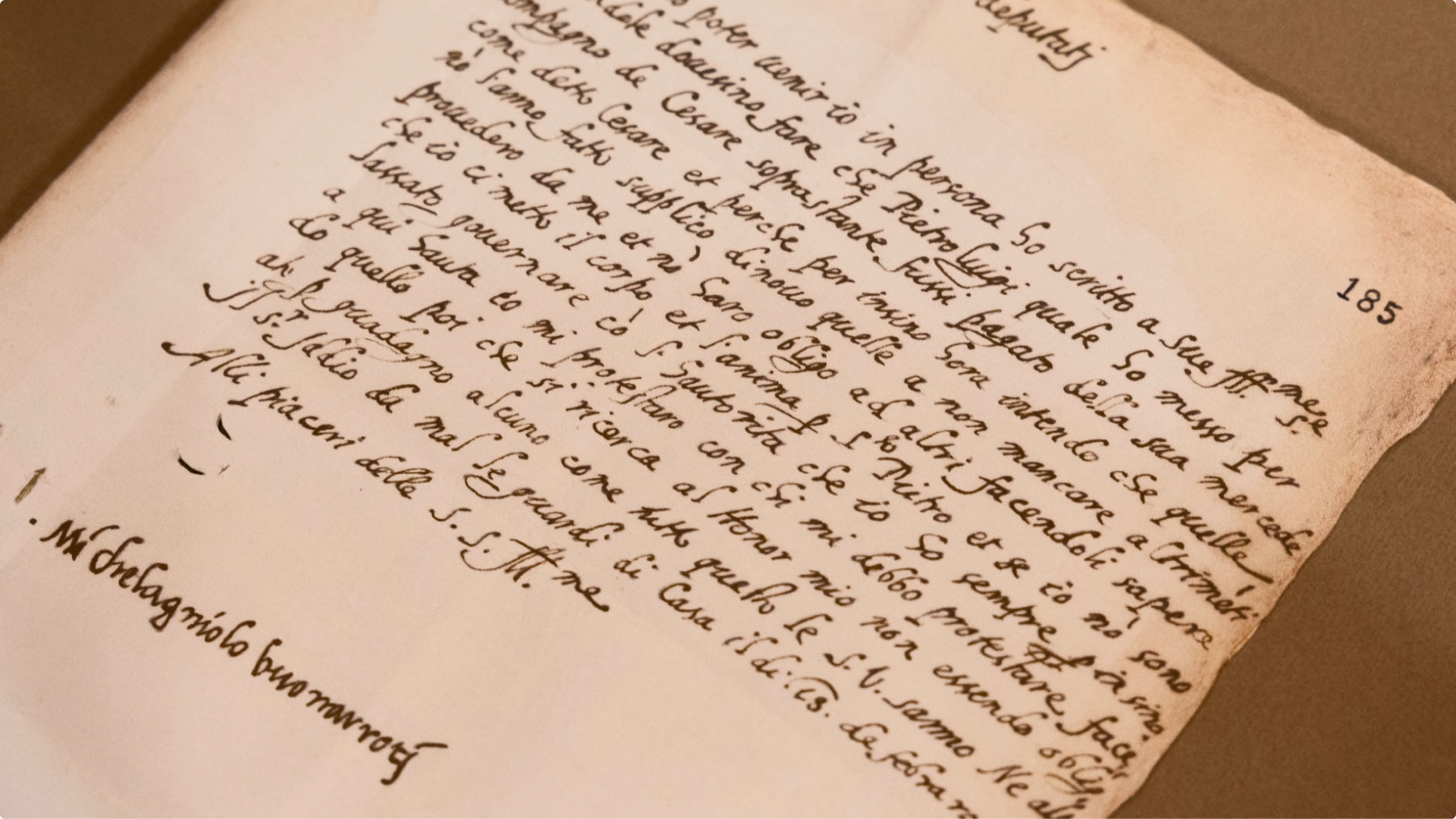A handwritten letter in Italian, signed at the bottom by Michelangelo Buonarroti, with the page number 185 printed in the upper right corner.
